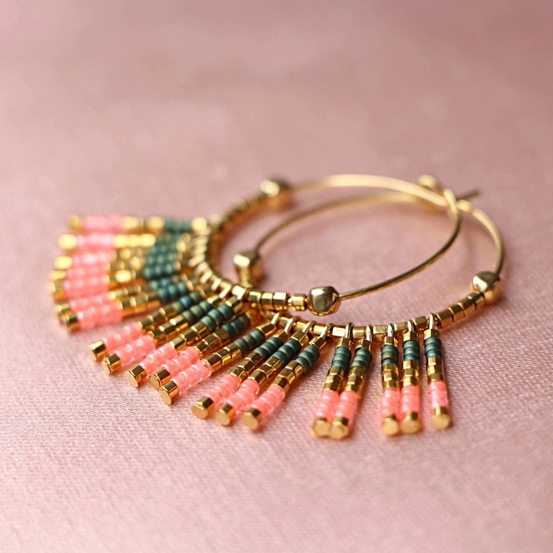 May include: Gold hoop earrings with a fringe of pink and green beads.
