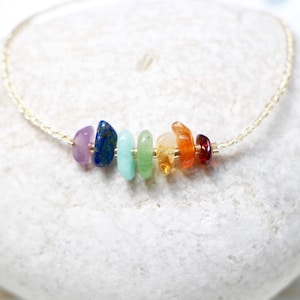 Puede incluir: Un collar de cadena dorada con siete piedras preciosas de diferentes colores, incluyendo amatista, lapislázuli, aventurina, citrino, cornalina y jaspe rojo.