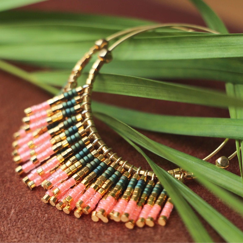 May include: Gold hoop earrings with a fringe of pink and green beads.
