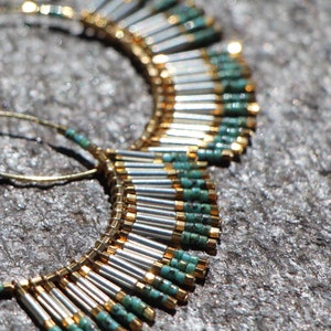 May include: A pair of hoop earrings with a fringe of silver and turquoise beads. The earrings are made of gold wire and have a delicate, bohemian style.