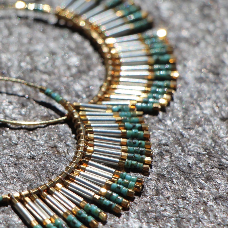 May include: A pair of hoop earrings with a fringe of silver and turquoise beads. The earrings are made of gold wire and have a delicate, bohemian style.