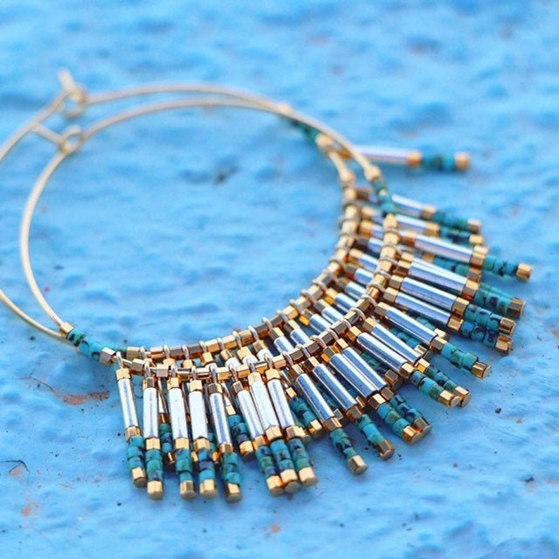 May include: Gold hoop earrings with a fringe of turquoise and silver beads.