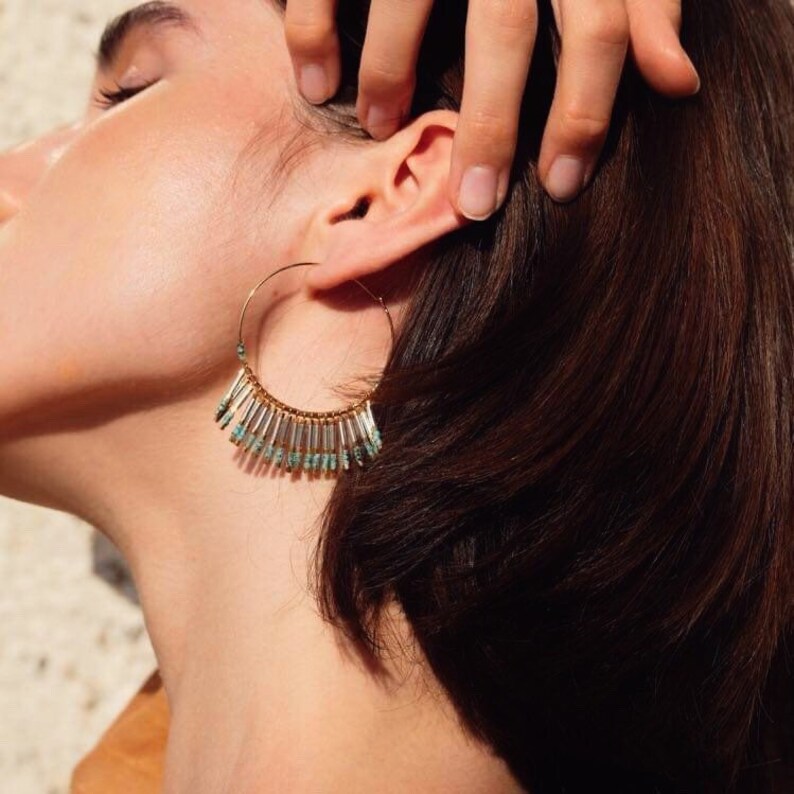 May include: Gold hoop earrings with a fringe of turquoise and silver beads.