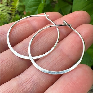 May include: A pair of silver hoop earrings with a hammered finish. The hoops are simple and elegant, and they would make a great everyday accessory.