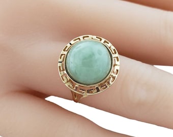 May include: A gold ring with a green jade stone set in a geometric design.