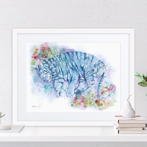 a framed watercolor painting of a tiger, with a white frame and a white shelf below it.