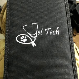 May include: Black canvas case with a white stethoscope and paw print design. The text "Vet Tech" is printed in white on the case.