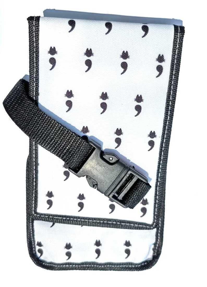 May include: A white canvas pouch with a black adjustable strap and a black plastic buckle. The pouch has a repeating pattern of black semicolon symbols.
