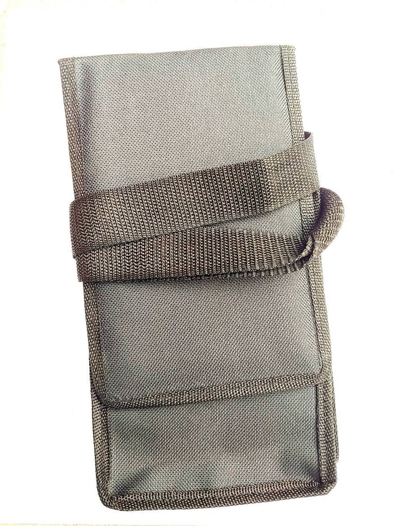 May include: A gray canvas carrying case with a black strap and a zippered closure. The case is designed to hold and protect small items.