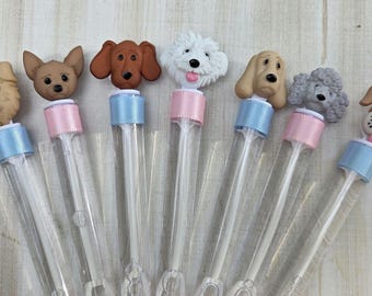 May include: A collection of seven clear bubble wands, each topped with a different dog-shaped figurine. The figurines vary in color and breed, with details like floppy ears and expressive eyes. The wands have blue and pink ribbon accents.