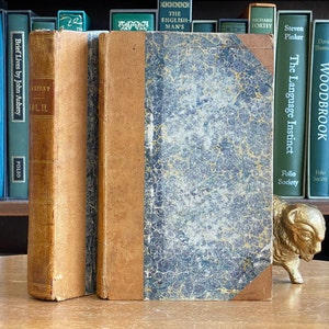 May include: Three antique books with marbled covers and gold lettering. The books are titled "Brief Lives by John Aubrey" and "The Language Instinct".