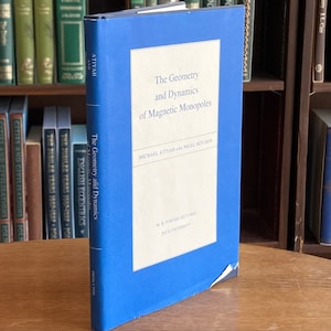 May include: A blue hardcover book titled "The Geometry and Dynamics of Magnetic Monopoles" by Michael Atiyah and Nigel Hitchin. The book is part of the W.R.  Sower Lectures series at Rice University.