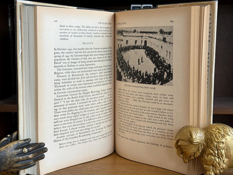 K&ouml;nnte beinhalten: Ein aufgeschlagenes Buch mit gealterten, vergilbten Seiten, das Text und ein Schwarz-Wei&szlig;-Foto einer Menschenmenge enth&auml;lt. Ein goldfarbenes Bison-Buchst&uuml;tze liegt auf der rechten Seite. Das Buch tr&auml;gt den Titel "The Black Book".