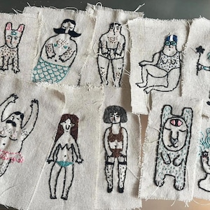 Könnte beinhalten: Eine Sammlung von neun rechteckigen Stoffaufnähern mit handgestickten Illustrationen. Die Motive zeigen eine Katze, einen Wassermann, eine Figur in Unterwäsche, einen Schwimmer, eine Hexe, einen Tänzer im Tutu, einen Bikini, eine Person und ein Wesen.