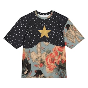 Puede incluir: Una camiseta de manga corta con una sección superior negra con lunares blancos y una estrella dorada central. La sección inferior muestra un fondo azul claro con una caja torácica humana, flores rojas y pájaros negros.