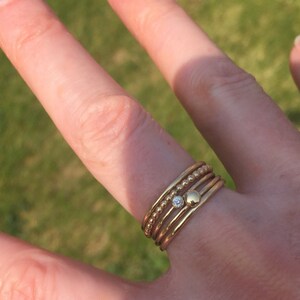 May include: A set of five gold stacking rings with a single small diamond ring in the center.