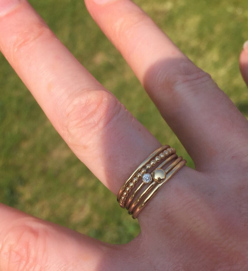 May include: A set of five gold stacking rings with a single small diamond ring in the center.