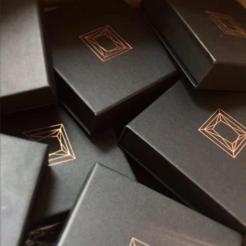 May include: A stack of black gift boxes with a gold geometric design on the top of each box.