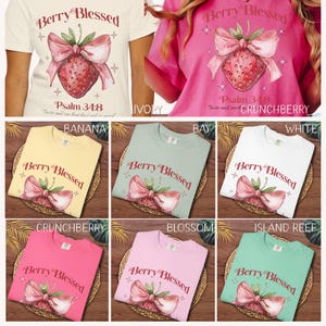 Op de afbeelding: Collectie t-shirts in diverse kleuren, elk met een aardbei-ontwerp met een strik en de tekst "Berry Blessed" en "Psalm 34:8". Kleuren zijn ivoor, banaan, baai, wit, crunchberry, blossom en island reef.