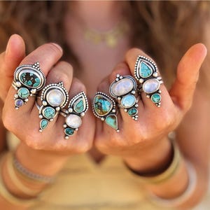 May include: Hands displaying several silver rings with turquoise and white gemstones. The rings have intricate designs and are the focal point of the image. Text on the left side promotes a silversmith workshop.