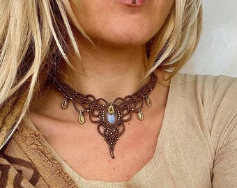 May include: A brown macrame choker necklace with a light blue gemstone pendant and gold accents. The necklace is worn by a person with blonde hair.