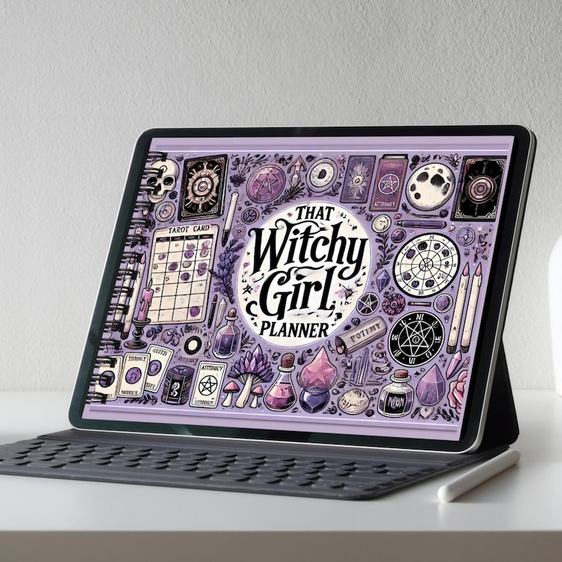 Op de afbeelding: Een digitale tablet met een paars en wit plannerontwerp met de tekst "THAT Witchy Girl PLANNER". Het ontwerp bevat tarotkaarten, drankflessen en andere mystieke elementen. De tablet staat op een toetsenbordhoes.