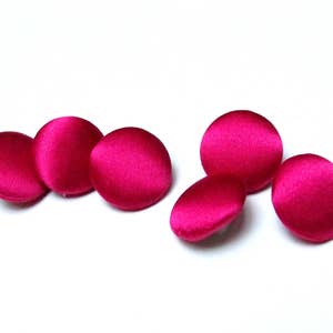Op de afbeelding: Vijf ronde, roze knopen met een stoffen bekleding.