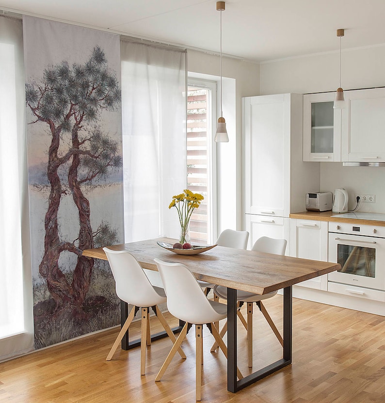 May include: A dining room with a wooden table and four white chairs. The table has a live edge and black metal legs. The room has white walls and a window with blinds. There is a curtain with a painting of trees on it.