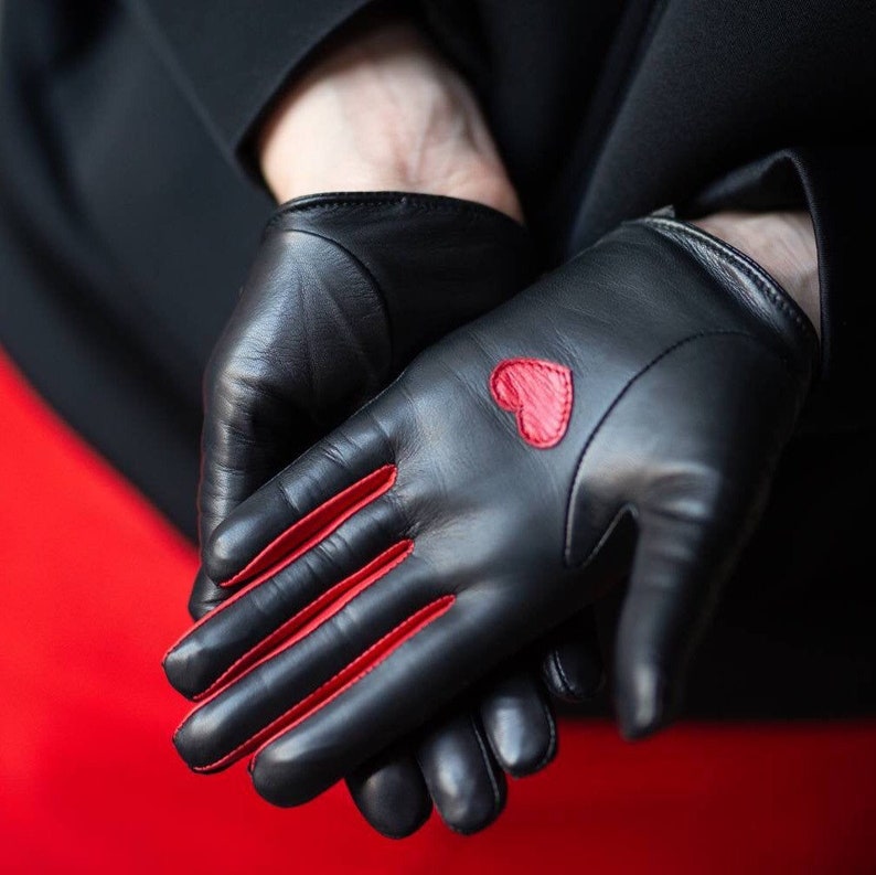 May include: A pair of black leather gloves with red stitching and a red heart on one glove.