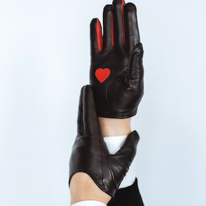 May include: A pair of black leather gloves with red accents. One glove has a red heart on the back of the hand.