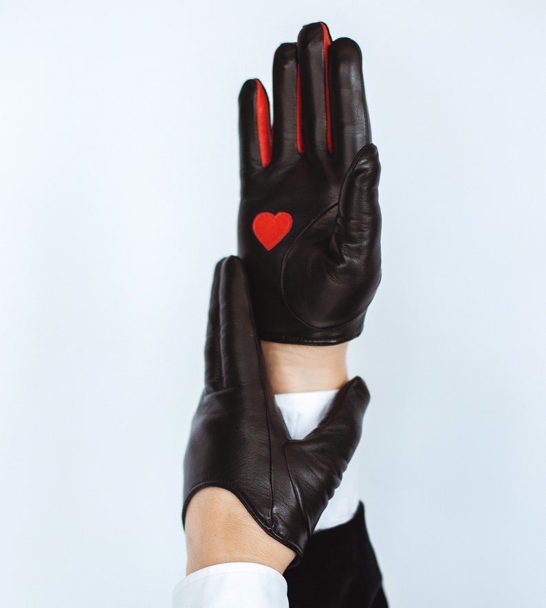 May include: A pair of black leather gloves with red accents. One glove has a red heart on the back of the hand.