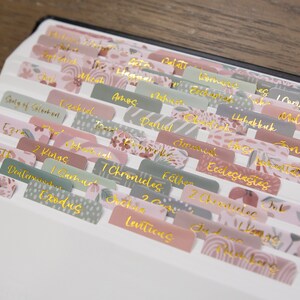 Peut inclure: Un ensemble d'onglets color&eacute;s &agrave; motifs floraux avec des lettres dor&eacute;es pour une Bible. Les onglets comprennent les noms des livres de la Bible tels que Gen&egrave;se, Exode, L&eacute;vitique, Nombres, Deut&eacute;ronome, Josu&eacute;, Juges, Ruth, 1 Samuel, 2 Samuel, 1 Rois, 2 Rois, 1 Chroniques, 2 Chroniques, Esdras, N&eacute;h&eacute;mie, Esther, Job, Psaumes, Proverbes, Eccl&eacute;siaste, Cantique des Cantiques, Isa&iuml;e, J&eacute;r&eacute;mie, Lamentations, &Eacute;z&eacute;chiel, Daniel, Os&eacute;e, Jo&euml;l, Amos, Abdias, Jonas, Mich&eacute;e, Nahum, Habacuc, Sophonie, Agg&eacute;e, Zacharie, Malachie.