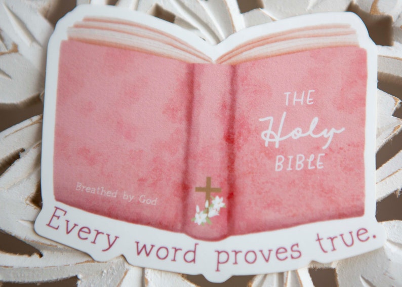 May include: A pink watercolor illustration of an open Bible with the words "The Holy Bible" and "Every word proves true." The Bible has a gold cross and flowers on the cover. The text "Breathed by God" is written on the bottom left corner.