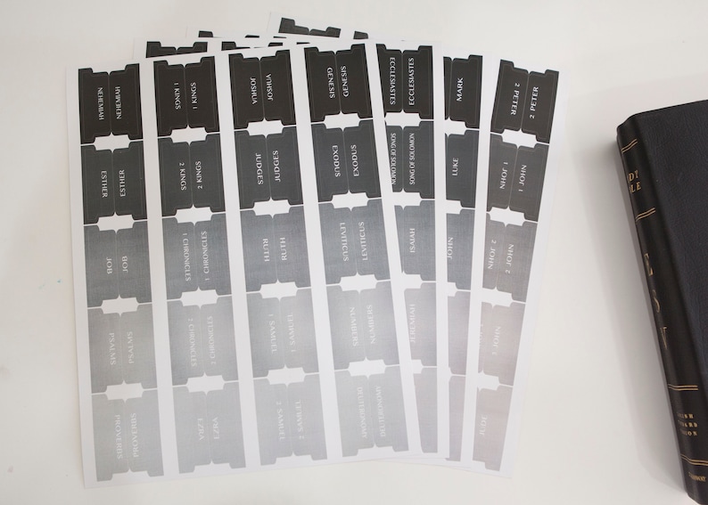 May include: A set of black and white Bible book tabs with a gradient design. The tabs are labeled with the names of the books of the Bible, including Genesis, Exodus, Leviticus, Numbers, Deuteronomy, Joshua, Judges, Ruth, 1 Samuel, 2 Samuel, 1 Kings, 2 Kings, 1 Chronicles, 2 Chronicles, Ezra, Nehemiah, Esther, Job, Psalms, Proverbs, Ecclesiastes, Song of Solomon, Isaiah, Jeremiah, Lamentations, Ezekiel, Daniel, Hosea, Joel, Amos, Obadiah, Jonah, Micah, Nahum, Habakkuk, Zephaniah, Haggai, Zechariah, Malachi, Matthew, Mark, Luke, John, Acts, Romans, 1 Corinthians, 2 Corinthians, Galatians, Ephesians, Philippians, Colossians, 1 Thessalonians, 2 Thessalonians, 1 Timothy, 2 Timothy, Titus, Philemon, Hebrews, James, 1 Peter, 2 Peter, 1 John, 2 John, 3 John, Jude, and Revelation.
