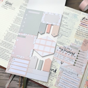 May include: A Bible open to a passage, with various pastel-colored sticky notes and tabs. The notes include shapes like rectangles, tags, and a hexagon, with floral and plaid patterns. Text on the notes reads "The Lord is my Shepherd."