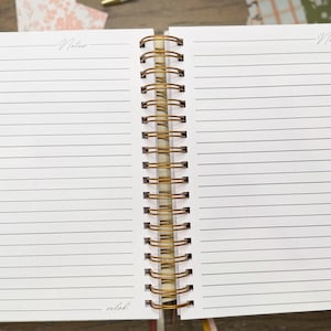 May include: An open spiral-bound notebook with white lined pages. Each page features the word Notes at the top and the word selah at the bottom. The binding is a metallic gold wire coil. The notebook includes colorful tabbed dividers on the side.