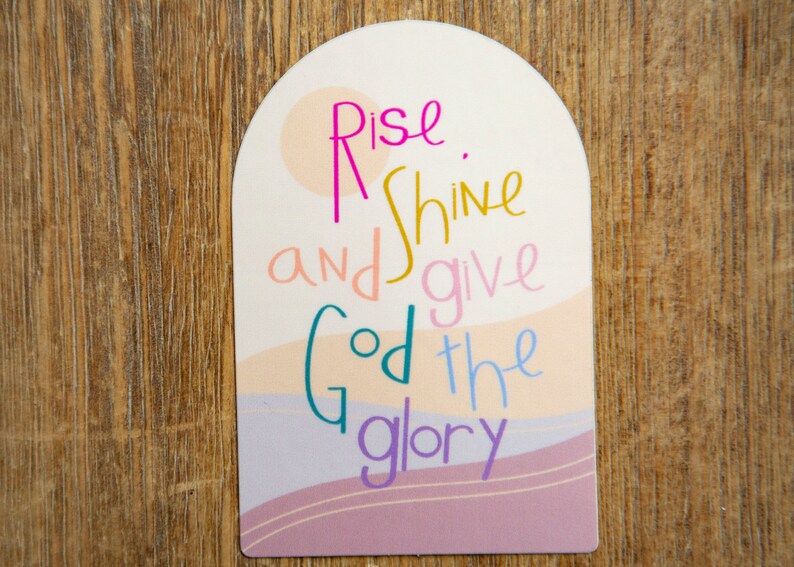 May include: A pink, white, and yellow arched sign with the text "Rise and shine and give God the glory".