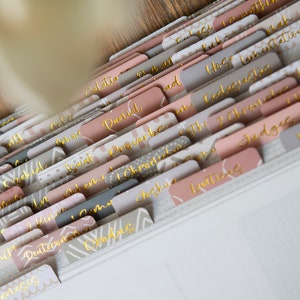 May include: A set of colorful, patterned dividers with gold lettering for a binder. The dividers are labeled with different books of the Bible, including Genesis, Exodus, Leviticus, Numbers, Deuteronomy, Joshua, Judges, Ruth, 1 Samuel, 2 Samuel, 1 Kings, 2 Kings, 1 Chronicles, 2 Chronicles, Ezra, Nehemiah, Esther, Job, Psalms, Proverbs, Ecclesiastes, Song of Solomon, Isaiah, Jeremiah, Lamentations, Ezekiel, Daniel, Hosea, Joel, Amos, Obadiah, Jonah, Micah, Nahum, Habakkuk, Zephaniah, Haggai, Zechariah, Malachi, Matthew, Mark, Luke, John, Acts, Romans, 1 Corinthians, 2 Corinthians, Galatians, Ephesians, Philippians, Colossians, 1 Thessalonians, 2 Thessalonians, 1 Timothy, 2 Timothy, Titus, Philemon, Hebrews, James, 1 Peter, 2 Peter, 1 John, 2 John, 3 John, Jude, and Revelation.