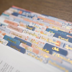 May include: A set of colorful, floral patterned tabs for a Bible or other book. The tabs are labeled with the names of books of the Bible, including Genesis, Exodus, Leviticus, Numbers, Deuteronomy, Joshua, Judges, Ruth, 1 Samuel, 2 Samuel, 1 Kings, 2 Kings, 1 Chronicles, 2 Chronicles, Ezra, Nehemiah, Esther, Job, Psalms, Proverbs, Ecclesiastes, Song of Solomon, Isaiah, Jeremiah, Lamentations, Ezekiel, Daniel, Hosea, Joel, Amos, Obadiah, Jonah, Micah, Nahum, Habakkuk, Zephaniah, Haggai, Zechariah, Malachi, Matthew, Mark, Luke, John, Acts, Romans, 1 Corinthians, 2 Corinthians, Galatians, Ephesians, Philippians, Colossians, 1 Thessalonians, 2 Thessalonians, 1 Timothy, 2 Timothy, Titus, Philemon, Hebrews, James, 1 Peter, 2 Peter, 1 John, 2 John, 3 John, Jude, and Revelation.