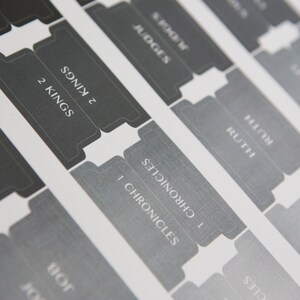 May include: Close-up of a set of gray and black book dividers with the names of books of the Bible printed on them, including 1 Samuel, Ruth, 1 Chronicles, 2 Kings, Judges, and Esther.