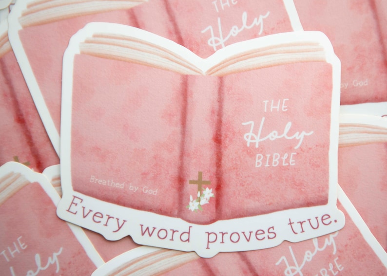 May include: A pink watercolor illustration of an open Bible with the text "The Holy Bible" and "Every word proves true." The illustration has a cross and flowers on the spine.