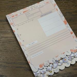 May include: A floral-themed notepad with a scalloped edge. The notepad features a light pink background with floral accents in peach, lavender, and gray. The notepad has sections for name, relatives, and other personal information.