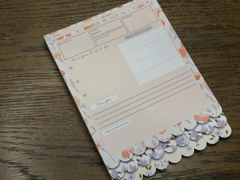 May include: A floral-themed notepad with a scalloped edge. The notepad features a light pink background with floral accents in peach, lavender, and gray. The notepad has sections for name, relatives, and other personal information.