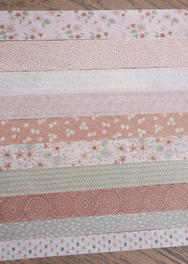 Pode incluir: Uma cole&ccedil;&atilde;o de tiras de papel estampadas em v&aacute;rios designs e cores. As tiras apresentam padr&otilde;es florais, pontilhados e geom&eacute;tricos em tons de rosa, p&ecirc;ssego e verde. Ideal para projetos de scrapbooking ou artesanato.