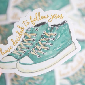 May include: A white sticker with a pair of teal green sneakers and the text "i have decided to follow jesus" in gold lettering.