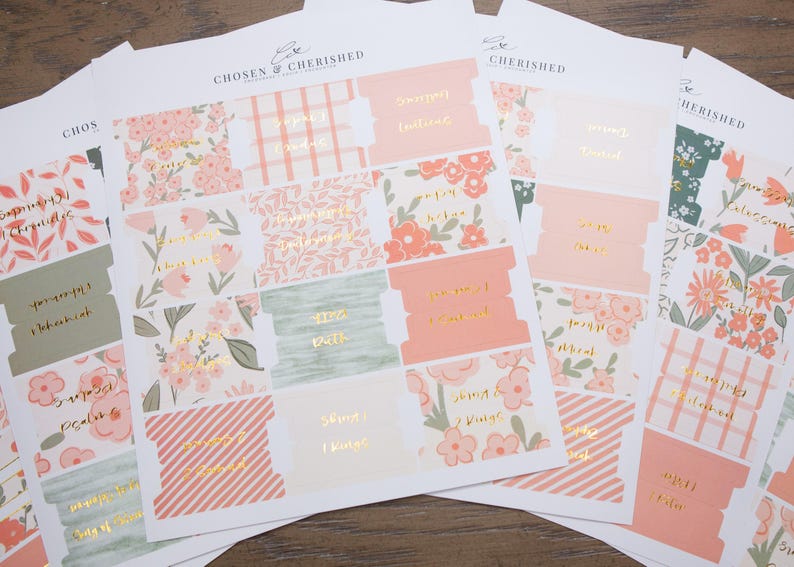 May include: A set of adhesive paper tabs for books, featuring various floral, plaid, and striped patterns in shades of peach, sage green, and white. Each tab includes gold foil lettering with book titles. The brand name Chosen & Cherished is printed at the top of each sheet.