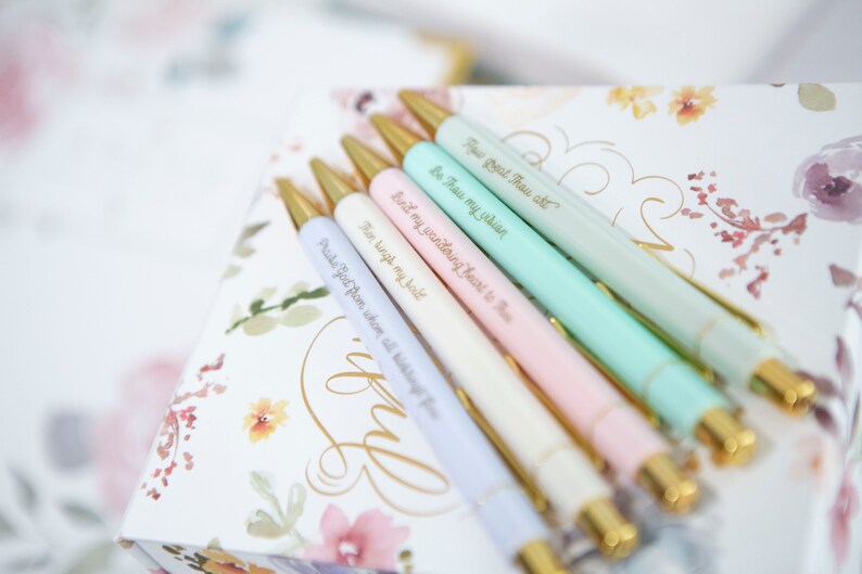 May include: Set of six pastel colored pens with gold accents and inspirational quotes engraved on each pen. The quotes are: "How Great Thou Art", "Be Thou My Vision", "Bind my wandering heart to Thee", "Then sing my soul", "Praise God from whom all blessings flow", and "I know".
