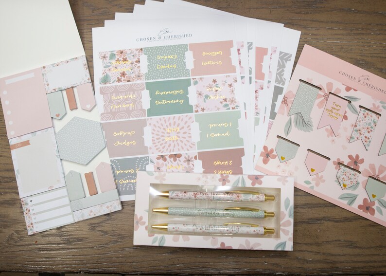 Peut inclure: Un ensemble de fournitures de papeterie &agrave; th&egrave;me floral rose et vert comprenant des autocollants, des blocs-notes, des stylos et des signets. Les autocollants pr&eacute;sentent des versets bibliques et le texte "Chosen & Cherished".