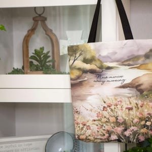 Puede incluir: Una bolsa de tela blanca con un dise&ntilde;o de paisaje de acuarela. La bolsa tiene correas negras y presenta el texto "New mercies every morning".