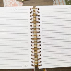 Puede incluir: Un cuaderno de espiral abierto con p&aacute;ginas blancas rayadas. Cada p&aacute;gina presenta la palabra Notes en la parte superior y la palabra selah en la parte inferior. La encuadernaci&oacute;n es un espiral de metal dorado. Incluye pesta&ntilde;as de colores.